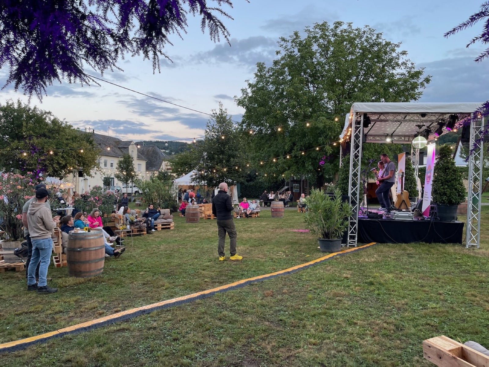 Gäste entspannen auf Palettenmöbeln vor der Bühne der Riesling Sommer Lounge